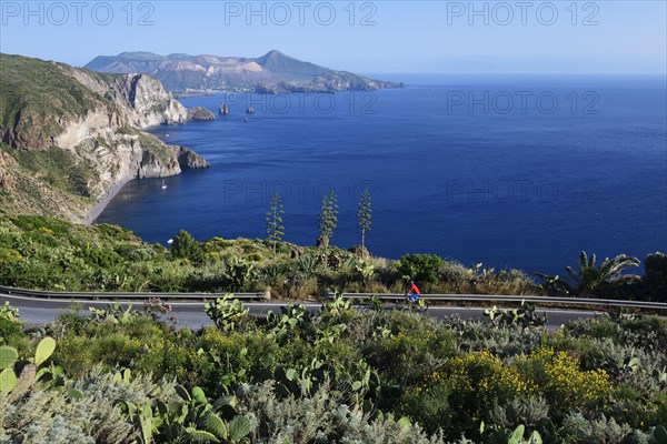 Cyclist on the Belvedere Quattrocchi with a view over the rocks Faraglione on the island Vulcano