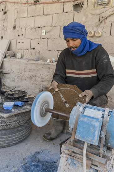 Bedouin preparing stone slabs with fossils