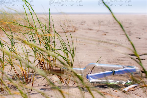 Bottle post on the beach between grasses