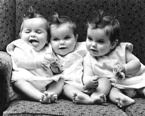 Three little girls sitting in an armchair