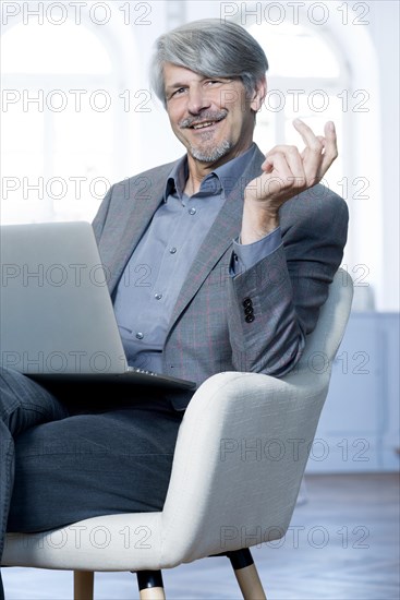 Man sits with laptop in his office chair