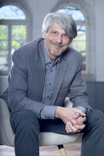 Man sits smiling in an armchair