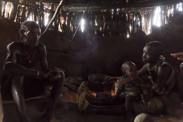 Family sits in mud hut