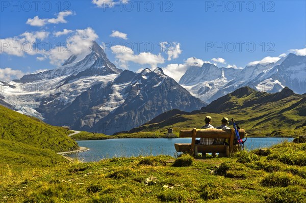 Hikers pausing on a wooden bench at lake Bachalpsee