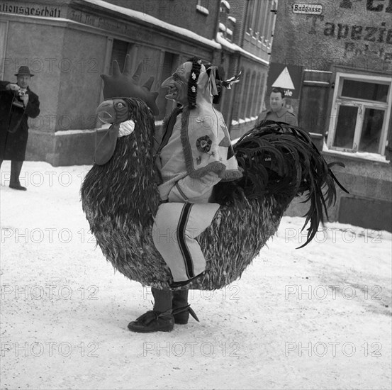 Man dressed as a cock walks through the snow-covered streets of Freiburg