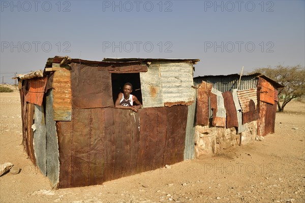 Local man looks out of the window of his poor corrugated iron hut