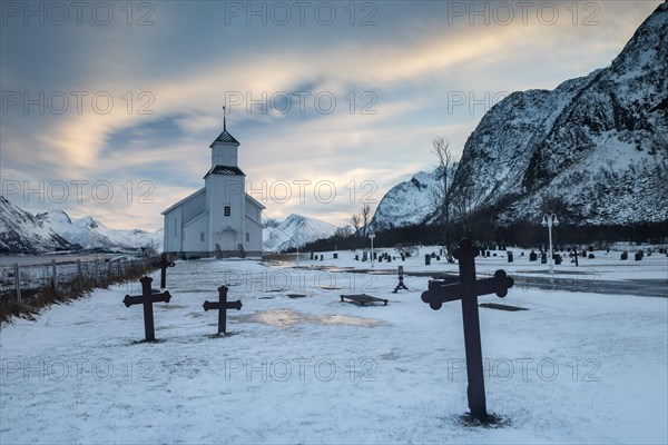 Church with icy cemetery at dusk