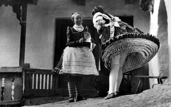 Two women in traditional costumes with many petticoats