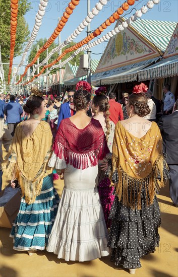 Spanish women with colorful flamenco dresses in front of marquees