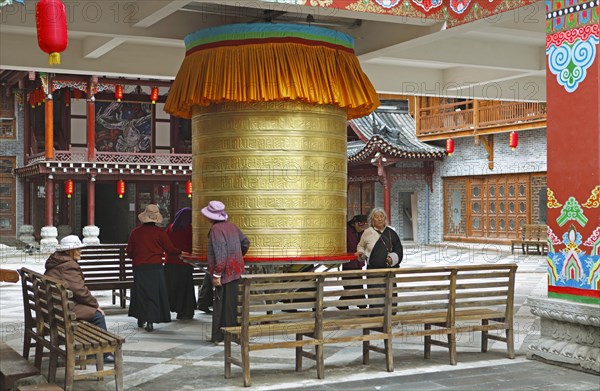 Women turn a prayer wheel