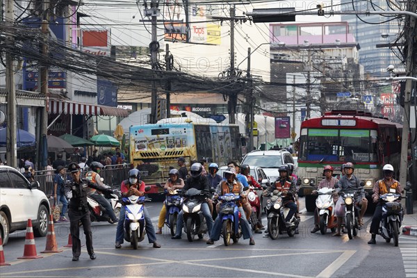 Many moped drivers are waiting at an intersection