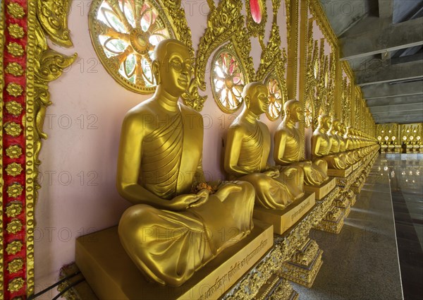 Row of golden Buddha statues in the corridor of the Phra Maha Chedi Chai Mongkhon Pagoda