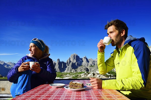 Hikers on the south side of the Three Peaks pause in front of the Lavaredo Hut