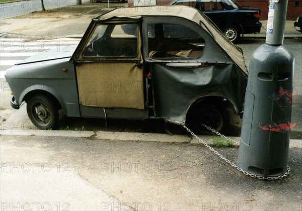 Broken car chained to a lamppost ca. 1970s