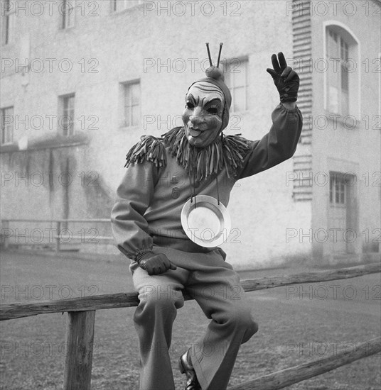 Disguised man sitting on a wooden banister and greeting