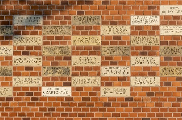 Memorial donor plaques on brick wall of Wawel Castle in Krakow