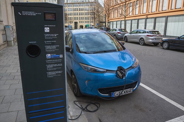 Electric car is charged at green electricity charging station with charging cable