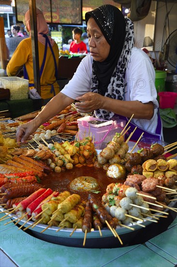 Saleswoman at the market stand with different skewers with meat and seafood