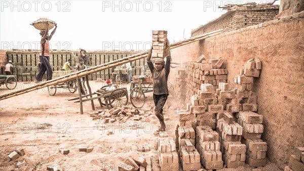 Workers with bricks on their heads in the brickyard