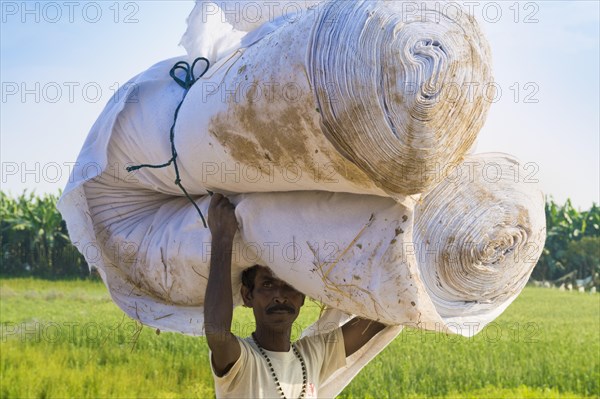 Nepalese Man from the Tharu ethnic group carrying big tissue roll on his head
