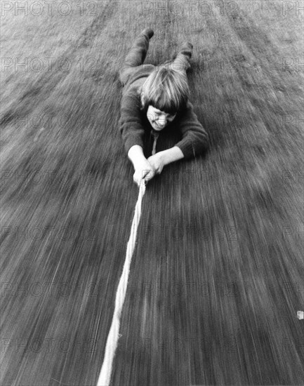 Boy is pulled over the ground on a rope