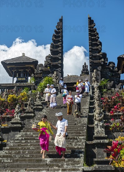 Balinese believers in traditional clothing go down stairs