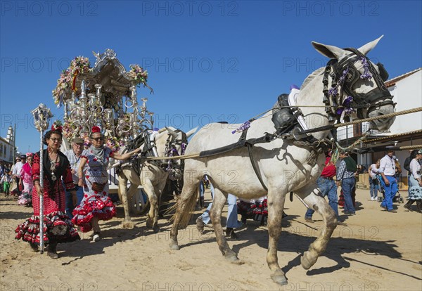 Women wearing colourful gypsy dresses besides a decorated carriage