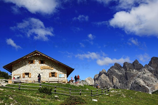 Hikers in front of the Lange Alm below the north face of the Three Peaks of Lavaredo
