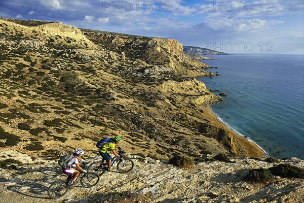 Two mountain bikers cycle along the rocky coast