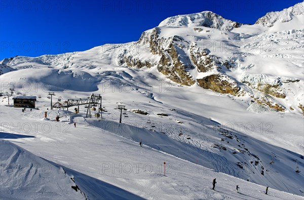 Skiers on the Langfluh ski slope in front of the snow-covered Alphubel