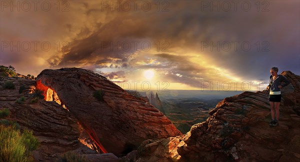 Girl at sunrise at the stone arch Mesa Arch