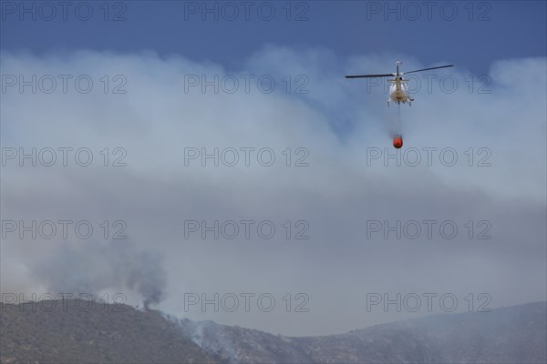 Helicopter flies with an extinguishing water tank to a fire