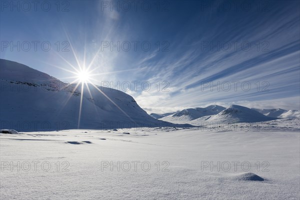 Sun over mountain range in the snow