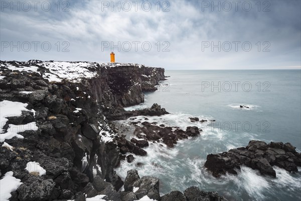 Orange lighthouse Ondverdarnes stands on a dark cliff