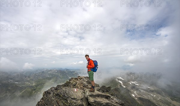 Hiker on the summit of the Hochgolling with rising fog