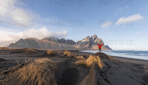 Man in red jacket stretches arms into the air