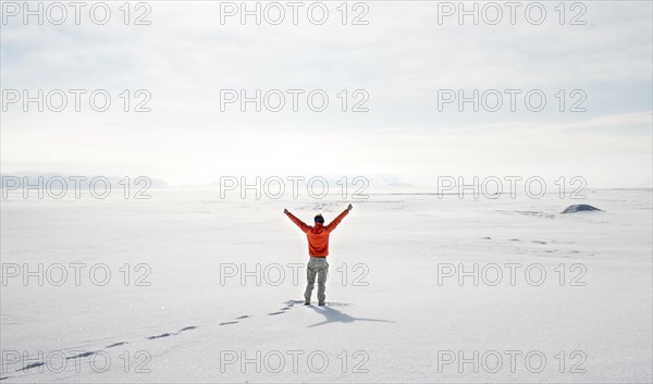 Young man stands alone in snowy landscape