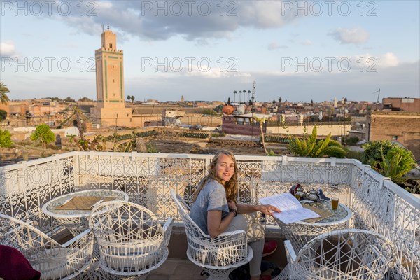 Young woman on a roof terrace reads the menu in the restaurant