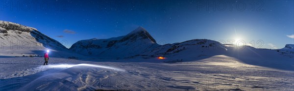 Person with tent on full moon in the snow