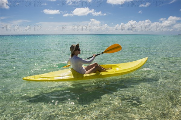 Female tourist kayaking in the turquoise waters of Tikehau