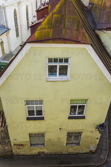 Top view of old architectural yellow with white trim and rusted standing seam sheet metal roof apartment building