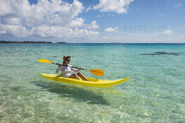 Female tourist kayaking in the turquoise waters of Tikehau