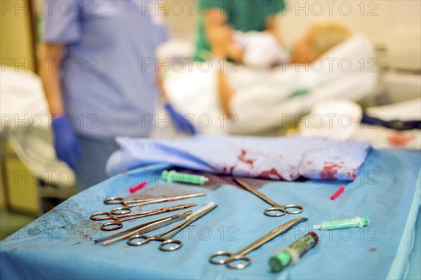 Silver gynecologist tools used during childbirth and mother and hospital staff in the background
