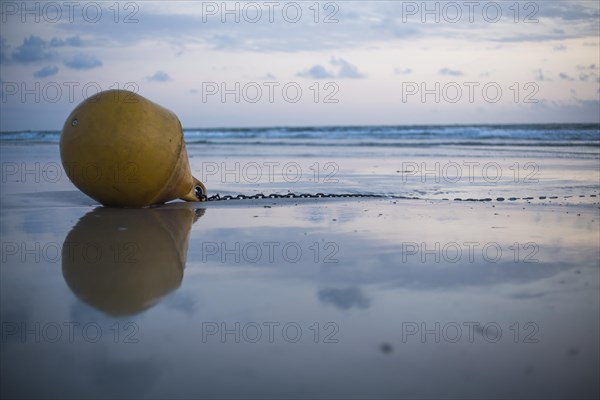 Buoy on the beach at sunset