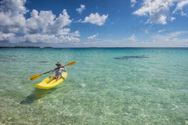 Female tourist kayaking in the turquoise waters of Tikehau