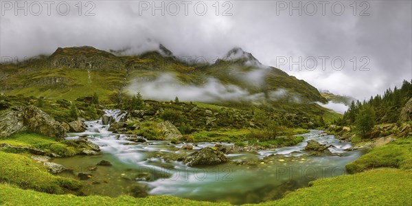 Fog clouds over mountain landscape with stream