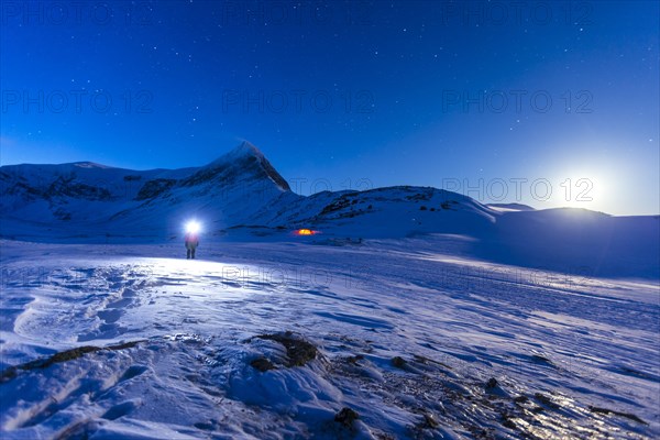 Person with tent on full moon in the snow