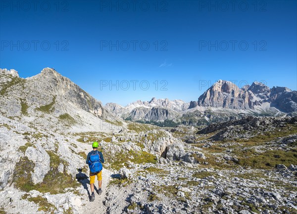 Hiker with climbing helmet on footpath to the Nuvolau