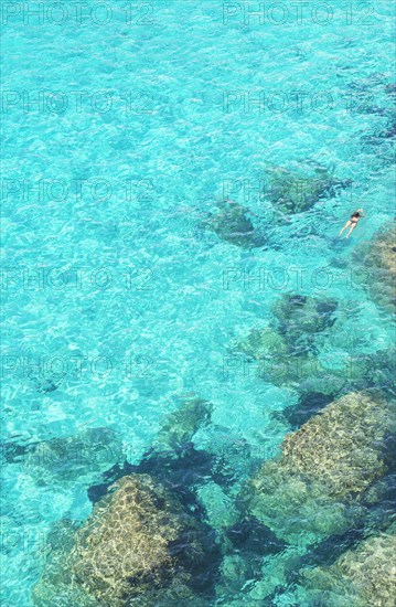 Person swimming in the emerald waters of Cala Mitjana