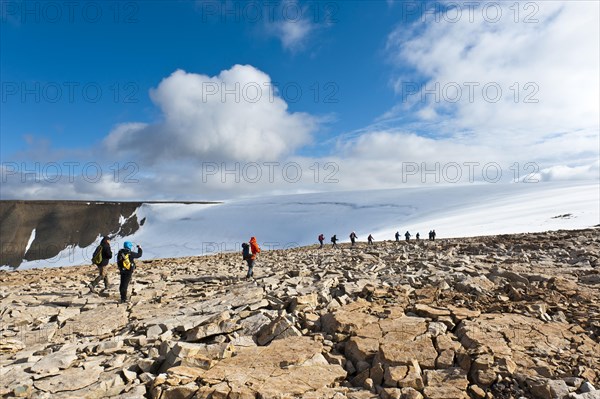 Hiking group in rocky terrain in front of Foxfonna glacier